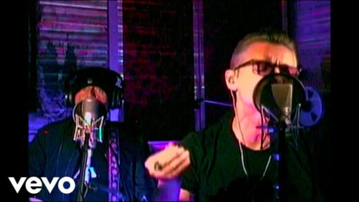 Das Bild zeigt einen Screenshot aus dem Musikvideo mit Sänger Dave Gahan im Vordergrund und Martin Gore im Hintergrund.